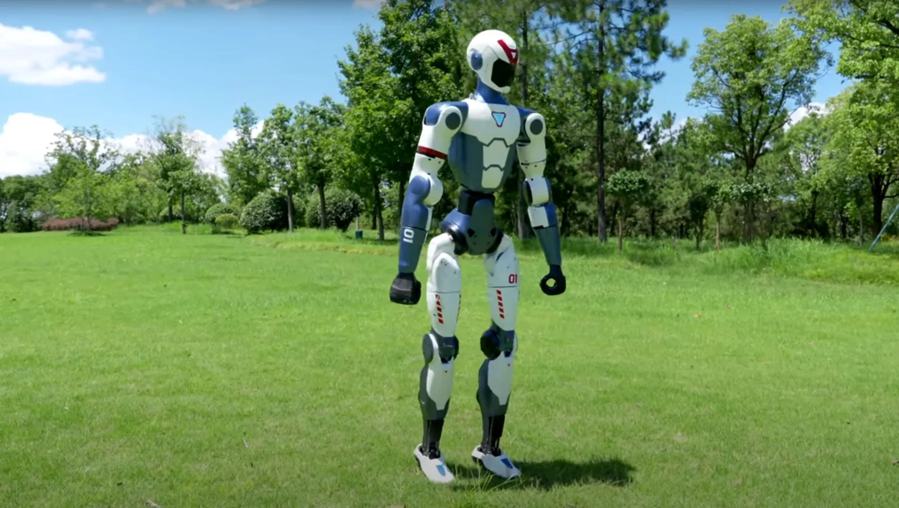 Unitree humanoid robot standing on green grass during outdoor AI mobility test