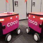 Two Coco automated delivery robots navigating a city sidewalk, designed for efficient and safe last-mile delivery.