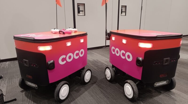 Two Coco automated delivery robots navigating a city sidewalk, designed for efficient and safe last-mile delivery.