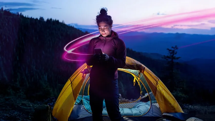 A girl holding a smartphone while using it – symbolizing access to T-Mobile Starlink satellite service in remote areas.
