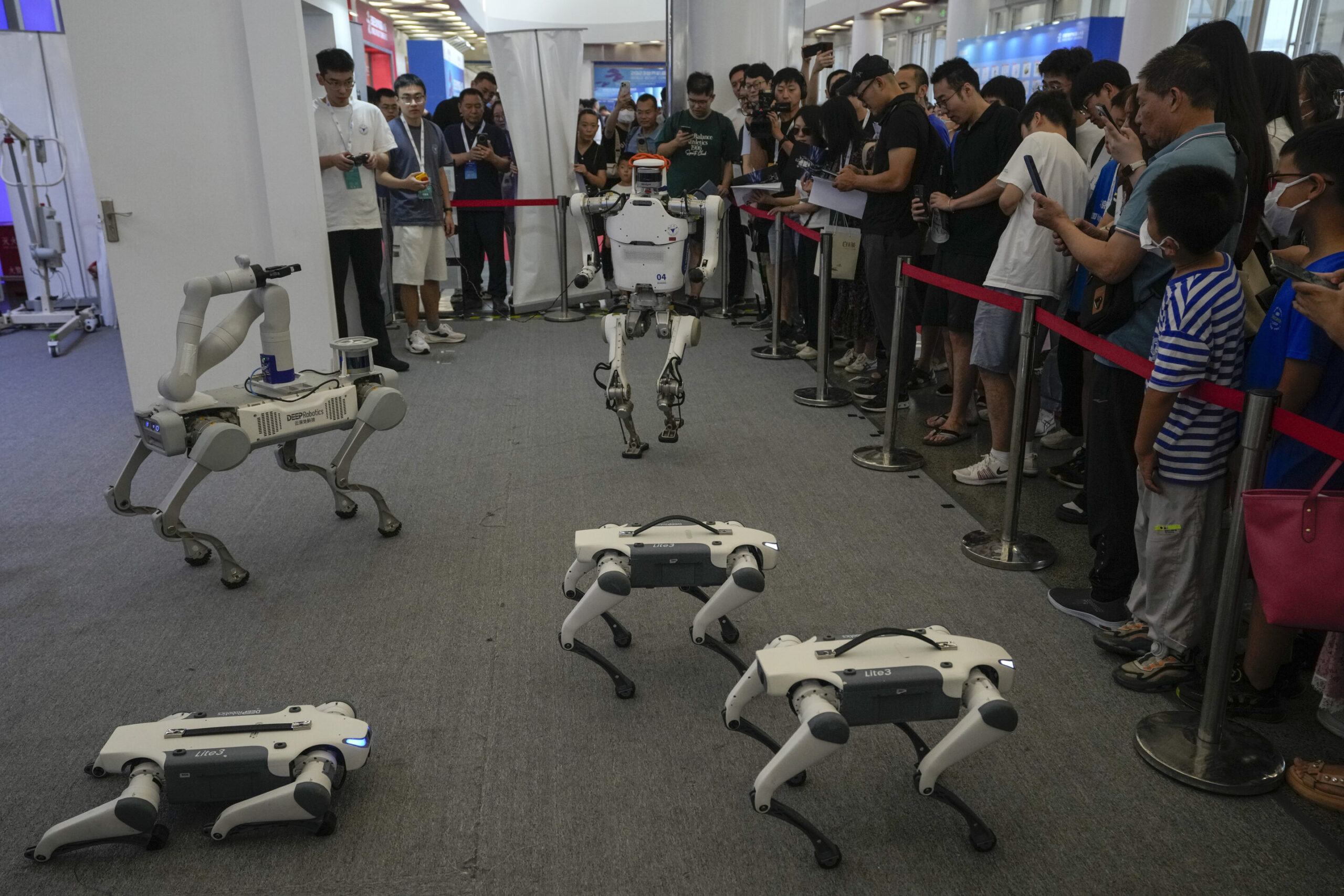 A group of DEEP Robotics' embodied intelligence robots performing a live demo at WAIC 2025 with a crowd watching