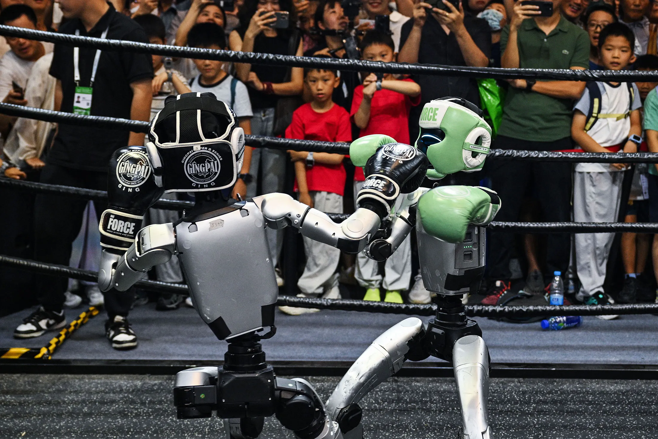 Two humanoid robots boxing at China's World AI Conference with Premier Li Qiang observing, symbolizing how China vies to unseat US in fight for $4.8 trillion AI market.