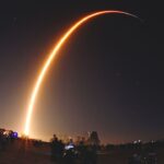 Long-exposure photograph of a rocket launch lighting up the night sky, symbolizing China's possible measures to counter Starlink satellites.