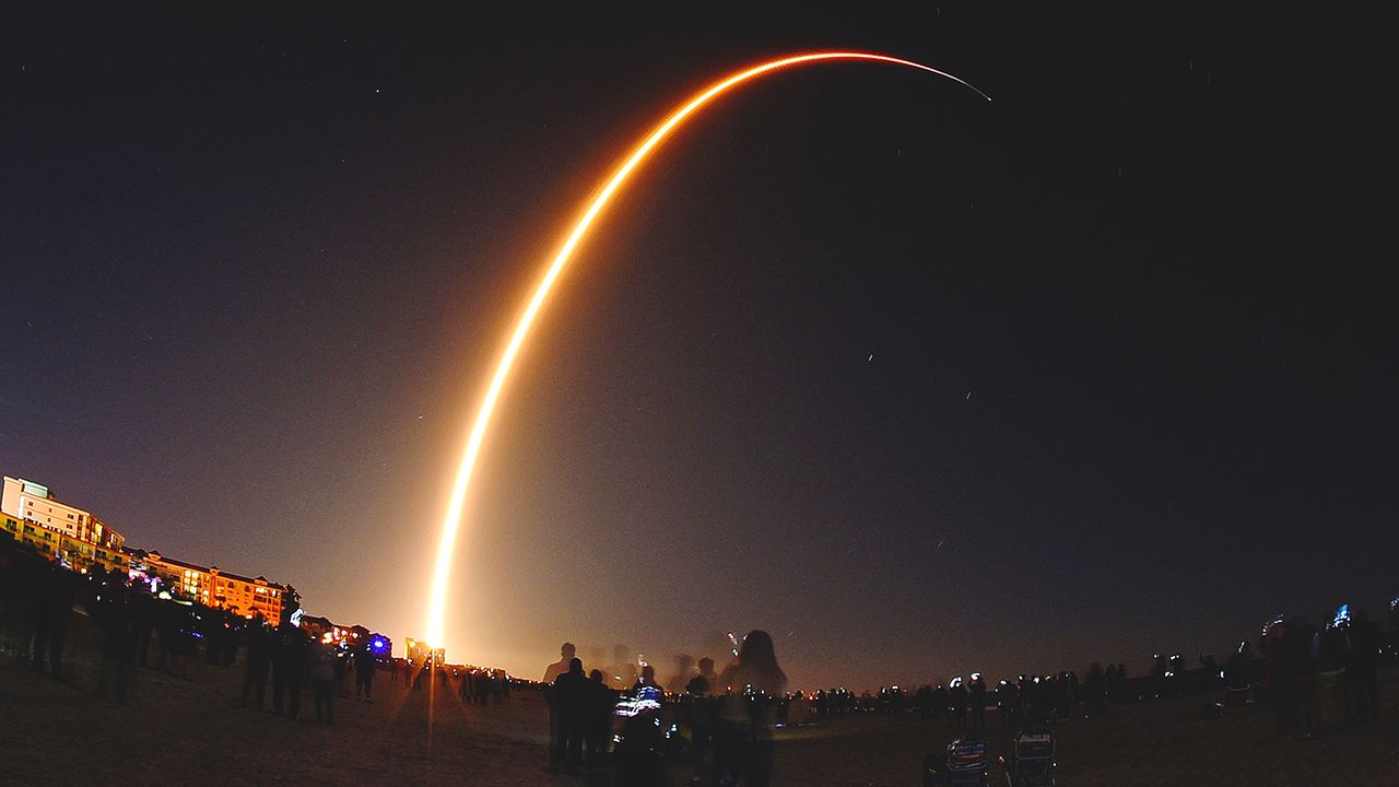 Long-exposure photograph of a rocket launch lighting up the night sky, symbolizing China's possible measures to counter Starlink satellites.