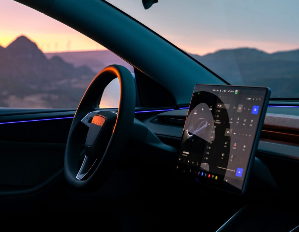 Interior of Tesla showing touchscreen with Tesla Grok AI update interface during sunset drive