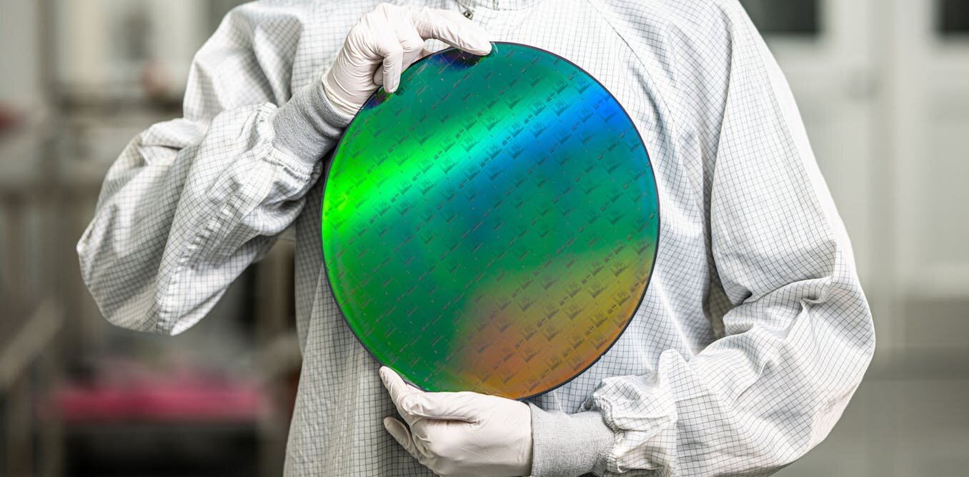 Technician holding a quantum chip wafer in cleanroom environment showcasing real-world quantum computing applications.