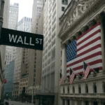 Wall Street view with New York Stock Exchange building and American flags during uncertainty over US government shutdown 2025.
