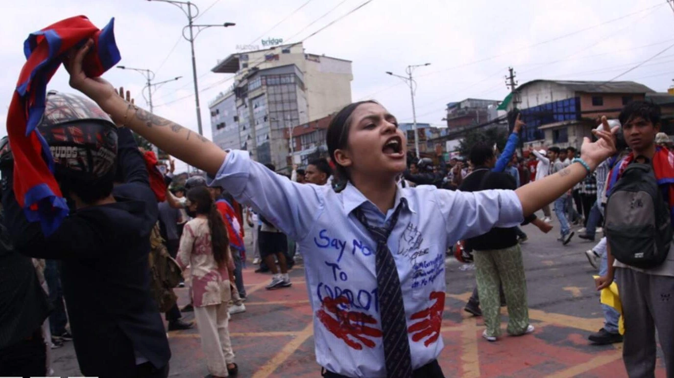 A young woman leads the Nepal Social Media Ban Protest in Kathmandu, raising her arms as crowds rally against government restrictions.