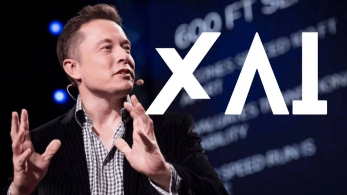 Elon Musk speaking in front of the xAI logo during announcement of xAI layoffs.