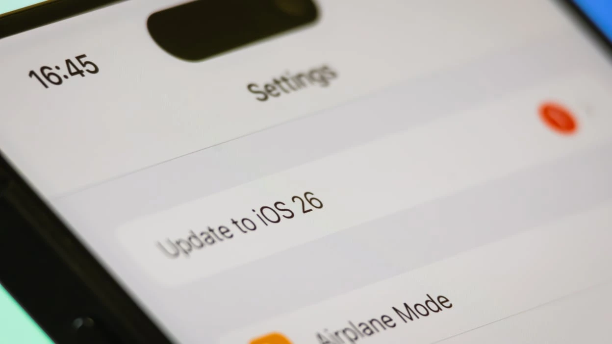 Close-up of iPhone screen showing update option to iOS 26 in settings menu, highlighting new features in iOS 26.