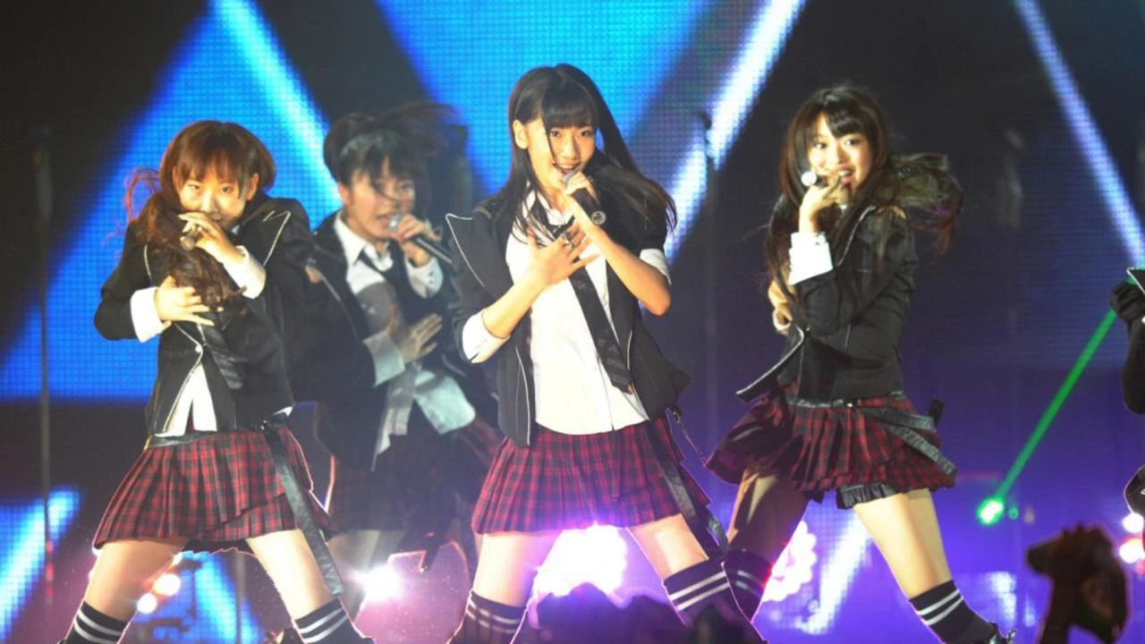 AKB48 members performing live on stage as fans react to their new AI song release.
