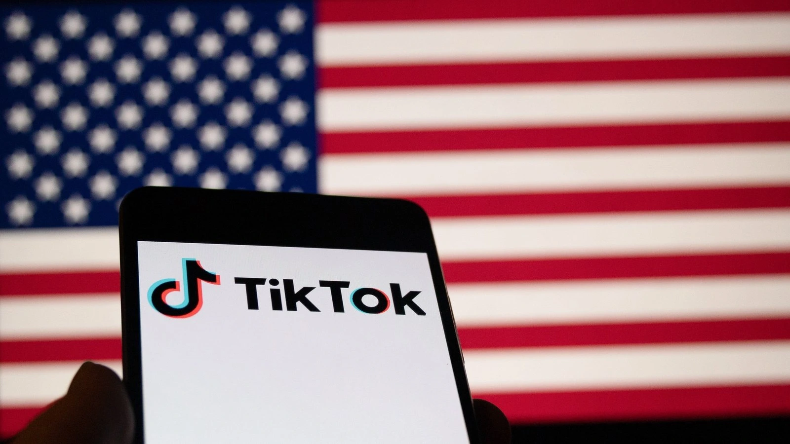 Smartphone showing TikTok logo in front of the U.S. flag, symbolizing the TikTok US operations deal and ongoing U.S.-China negotiations.
