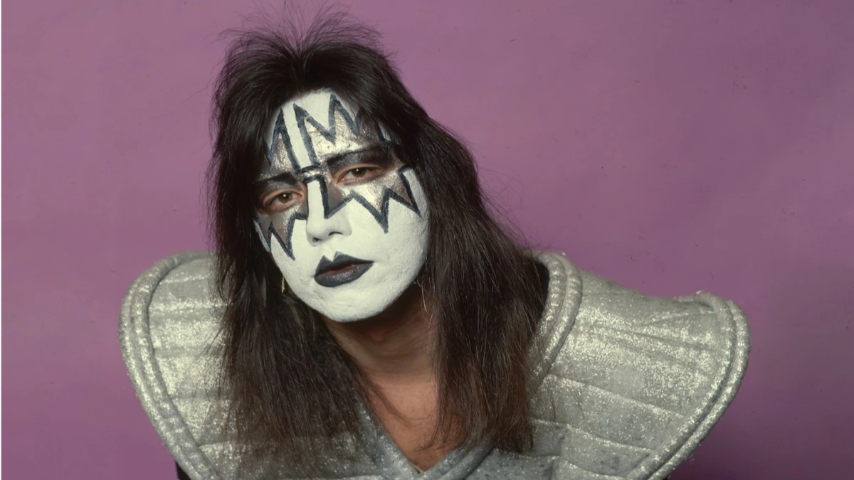 Ace Frehley performing live in signature Spaceman makeup during a Kiss concert, holding his Les Paul guitar under bright stage lights.