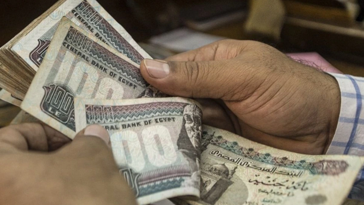 Two Egyptian men exchange cash at a government office counter, depicting the impact of Egypt inflation and the culture of “tea money” bribes in daily life.