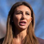 Alina Habba standing at a podium in a federal building after announcing her resignation as US attorney in New Jersey.