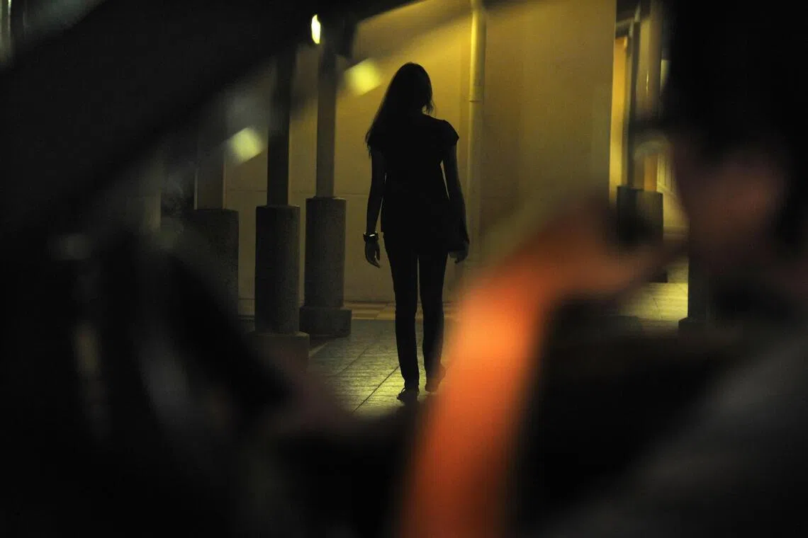 A silhouetted woman walks alone at night while a distant figure appears to watch her, illustrating concerns addressed by South Korea developing app that shows real time location of stalkers.