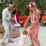 Gisele Bündchen and Joaquim Valente dance with their 1-year-old son during a cultural celebration in Tahiti as local musicians perform in the background.