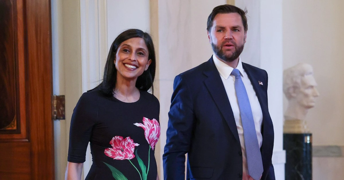 Second Lady Usha Vance and Vice President JD Vance stand together inside a government building, smiling during an official event following the announcement of the birth of their fourth child.
