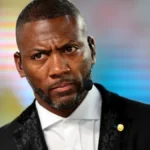 Ryan Clark appears on a television broadcast wearing a black suit and headset microphone during an ESPN studio segment.