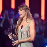 Taylor Swift reacts with an excited expression while holding an award on stage during a public appearance as discussion grows around her Toy Story 5 original song and early Oscar buzz.