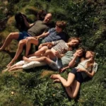 Prince William and Princess Kate relax on a grassy hillside with their three children during a summer family holiday, sharing a candid outdoor moment in newly released summer photos.