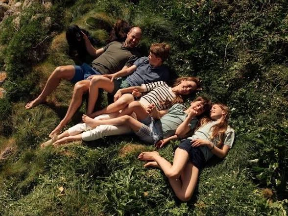 Prince William and Princess Kate relax on a grassy hillside with their three children during a summer family holiday, sharing a candid outdoor moment in newly released summer photos.